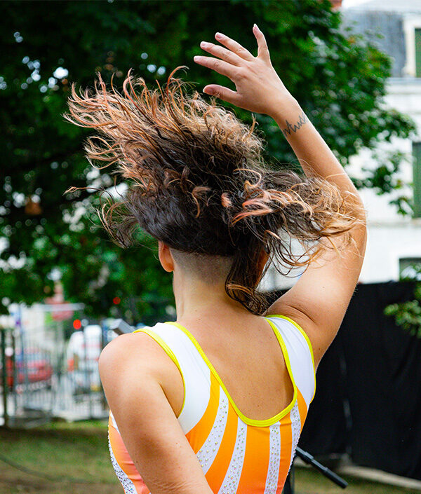 Artiste en mouvement sur scène, corps et bras levé, incarnant une performance vocale et corporelle